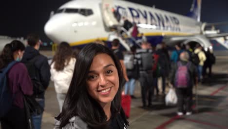 Woman-standing-in-front-of-a-plane,-ready-to-travel