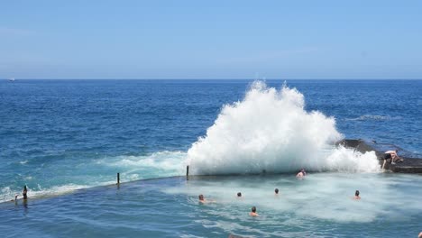 Ola-Rompiendo-Sobre-El-Malecón-En-La-Piscina-Natural-Empujando-A-Los-Nadadores