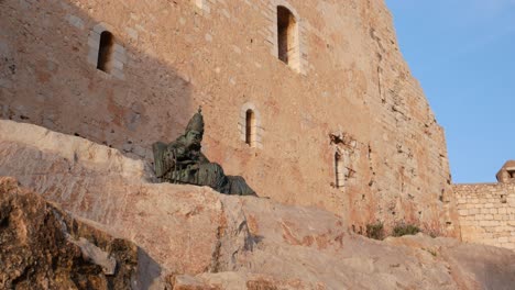 Tilt-down-from-the-fortress-walls-to-the-statue-of-Benedict-XIII,-Papa-Luna,-in-Peñíscola,-Spain