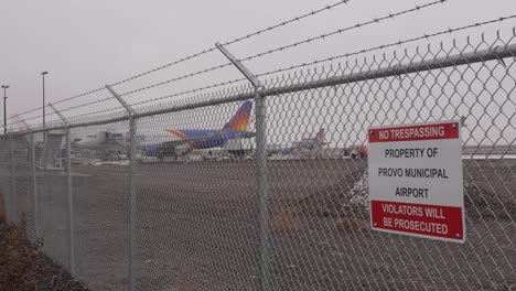 Avión-En-La-Puerta-Detrás-De-La-Valla-En-El-Aeropuerto-Municipal-De-Provo---Nieve,-Aguanieve-Y-Lluvia