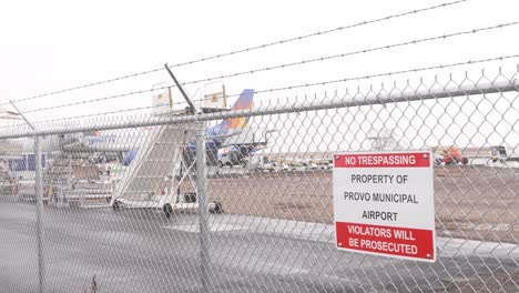 Kein-Hausfriedensbruch-Schild-Am-Zaun-Des-Städtischen-Flughafens-Provo-Mit-Einem-Flugzeug-Der-Allegiant-Airlines-Am-Abflug--Oder-Ankunftstor-An-Einem-Schnee-,-Graupel--Und-Regentag