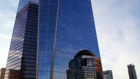 Aerial-view-rising-close-to-the-reflecting-windows-of-the-One-World-Trade-Center,-in-sunny-NYC