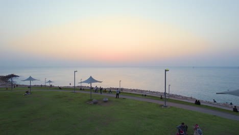 People-relax-on-a-grassy-hill-in-front-of-the-sea-during-a-red-sunset-on-Christmas-week-22-23