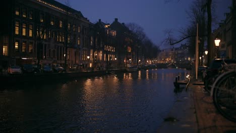 Un-Día-Lluvioso-En-El-Centro-De-La-Ciudad-De-Amsterdam,-Toma-Nocturna-De-Un-Paisaje-Urbano-Con-Edificios-Y-Un-Canal