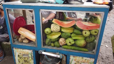 Comida-Callejera-Rujak,-Ensalada-De-Frutas-Picantes,-Vendedor-En-Indonesia-Bali-Sudeste-Asiático-Prepara-Un-Plato-Popular-Tradicional-Con-Papaya,-Carambola,-Mango,-Pepino-Y-Salsa-En-La-Playa-De-Saba,-Gianyar