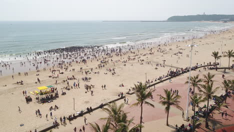 Drohnenaufnahme-Von-Großen-Menschenmengen-Am-Strand-Von-Durban-In-Südafrika,-Menschen-Im-Indischen-Ozean,-Die-In-Den-Wellen-Schwimmen