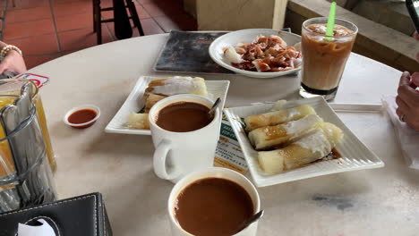 Chinese-style-snacks-with-hot-and-cold-drinks-on-the-table-with-female-hand-but-no-face