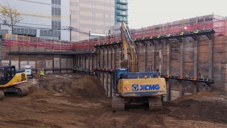 Drone-Flies-Through-Excavator,-Excavating-urban-land-at-Flushing-Queens-New-York