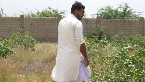 Rear-view-of-farmer-walking-in-the-farm-land