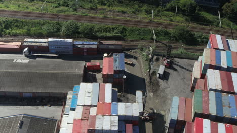 Toma-Aérea-De-Drones-De-Camiones-Conduciendo-Hacia-Un-Patio-De-Contenedores-De-Envío