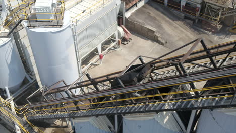 Aerial-drone-shot-of-Asphalt-mix-moving-up-a-conveyor-belt-to-be-loaded-into-a-truck-at-an-asphalt-plant