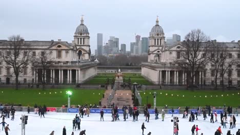 Gente-Patinando-Sobre-Hielo-En-El-Antiguo-Colegio-Naval-Real-De-Greenwich-Frente-A-Canary-Wharf,-Londres,-Reino-Unido