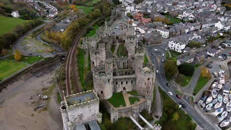 Historic-Conwy-castle-aerial-view-of-Landmark-town-ruin-stone-wall-battlements-tourist-attraction-slow-descending-tilt-up