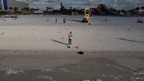 Drohnenaufnahme-Eines-Mannes,-Der-An-Einem-Strand-Steht-Und-Die-Landschaft-Enthüllt