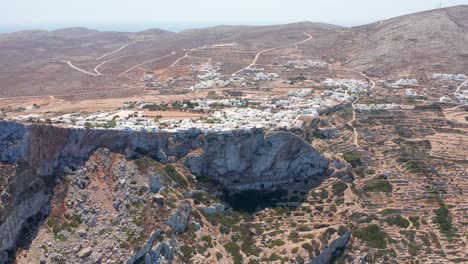 Aerial-wide-Panning-shot-Folegandros-white-Town-on-rocky-hillside-and-Mountain-cliffs