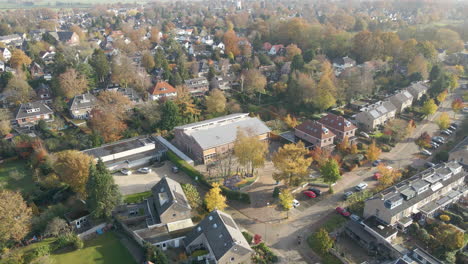 Aerial-of-a-grade-school-with-children-playing-on-square-on-a-lovely-autumn-day---drone-flying-backwards
