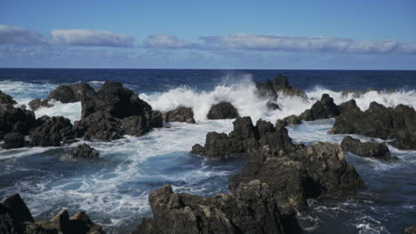 Waves-smash-into-rocky-shoreline-near-Porto-Moniz-Portugal,-slow-motion
