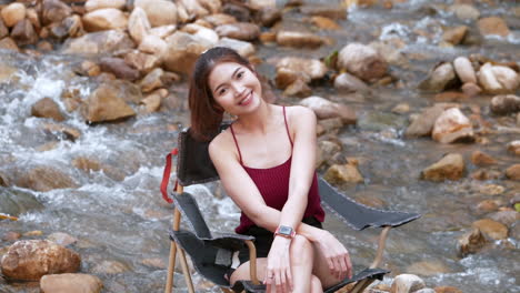 Asiatische-Frau-In-Rot-Sitzt-Auf-Einem-Stuhl-Mit-Großen-Felsen-Und-Wasser-Spritzt-Langsam-Zum-Entspannen-Und-Glück-Im-Feriensommer
