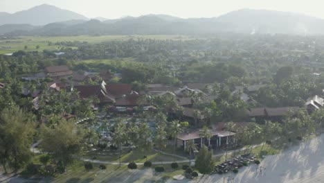 Tracking-shot-from-close-up-to-full-view-Langkawi-coastline-with-buildings,-palm-trees,-coast-and-sea,-daylight,-no-people,-and-an-aerial-view