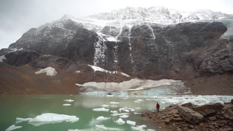 Female-on-Glacial-Lake-Coast-Under-Angel-Glacier,-Mount-Edith-Cavell,-Jasper-National-Park-Canada-on-Cold-Autumn-Day