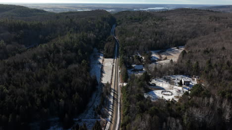 Forest-highway-through-an-old-coniferous-forest-in-late-winter---aerial-drone-shot