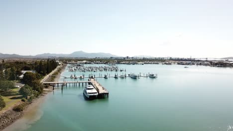 Drone-aerial-slow-pan-over-blue-water-harbour-on-a-sunny-day-with-a-park