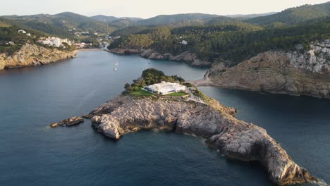 wealthy-private-home-on-island-in-cala-benirras,-ibiza-aerial-view-pan-down