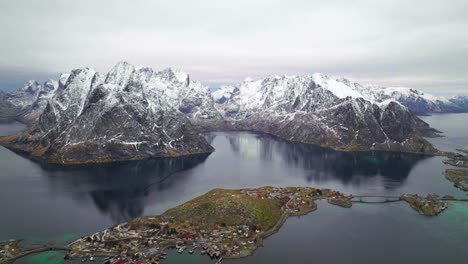 Moskenesøya-Schneebedeckte-Berge-Luftaufnahme-über-Das-Idyllische-Fischerdorf-Reine-Norway