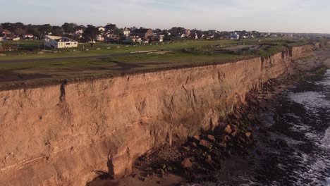 Aerial-shot-of-driving-car-over-steep-cliffs-and-ocean-during-sunset---Mar-del-Plata,Argentina