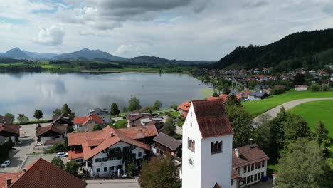 Hopfensee-lake-and-town-Hopenfen-town-in-Swabia-Bavaria-Germany-drone-aerial-over-church-tower