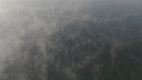 Scenic-aerial-flying-through-endless-mist-across-lake-surface