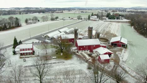 Aerial-orbit-of-red-barns-and-buildings-during-snowstorm