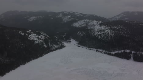 Vast-Frozen-Water-Of-Lake-à-l'Empêche-With-Scenic-Mountainscape-Near-Saint-Urbain,-Quebec,-Canada