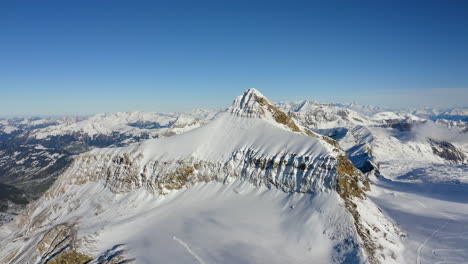Aerial-slow-descending-shot-facing-Oldenhorn-snow-caped-summit-overlooking-Tsanfleuron-glacier