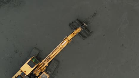Top-down-aerial-view-of-a-digger-moving-mud-on-a-construction-site