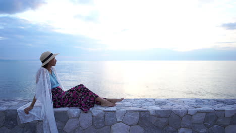 Stylish-Asian-Woman-Sitting-on-Rampart-by-The-Sea-and-Enjoying-in-Peace-in-View-on-Horizon,-Static-With-Copy-Space-Shot