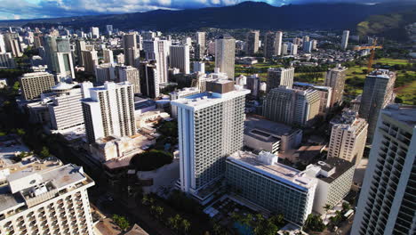 Drone-shot-flying-over-Honolulu-Hawaii-buildings-with-mountains-in-background