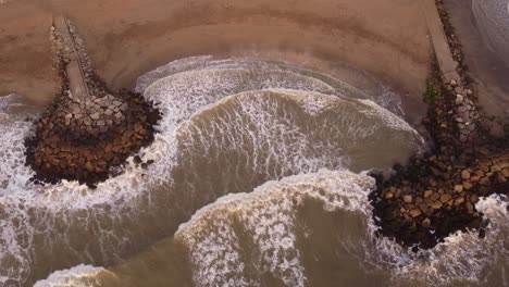 Aerial-top-down-of-powerful-water-waves-of-the-Atlantic-Ocean-reaching-sandy-beach-of-Mar-del-Plata-during-sunset,Argentina