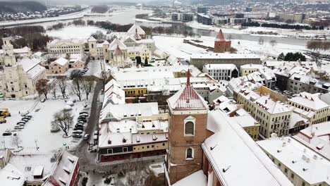 Iconic-old-town-of-Kaunas-city-covered-in-pure-white-snow,-flying-above-drone