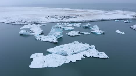 Aerial-view-of-massive-icebergs-floating-on-water-surface-of-glacier-lagoon-during-daytime---Jo-kulsa-rlo-n,Iceland