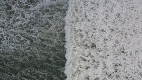 Wave-slowly-creeping-to-shoreline,-aerial-bird's-eye-view-following-wave-motion