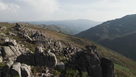 Flying-through-stones-on-hilltop,-idyllic-scenery-with-valley-and-mountain-layers,-Gerês-National-Park