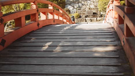Slide-shot-of-a-bridge-over-a-pond-in-a-Japanese-garden-in-Kyoto,-Japan-4K-slow-motion
