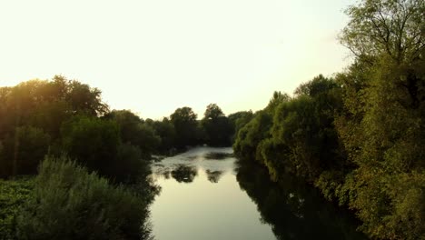 Aerial-drone-shot-flying-over-a-beautiful-calm-river-just-before-sunset
