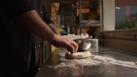 Chef-rolling-dough-on-a-restaurant-kitchen-table,-handheld-shot-on-isolated-action