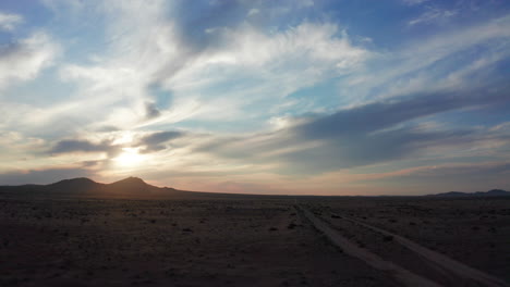 Desert-landscape-hyperlapse-during-a-colorful-sunset-against-the-distant-mountains---aerial-dolly-forward-wide-angle