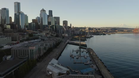 Drone-Flies-Towards-Downtown-Seattle-Skyline-during-Daylight-with-Mount-Rainier-in-Background,-Summer-Aerial