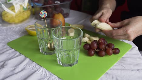 Cutting-a-banana-for-a-fresh-fruit-salad-in-clear-glasses
