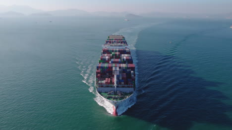 Aerial-front-view-of-a-loaded-container-cargo-vessel-traveling-over-ocean