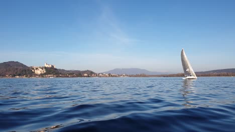 Low-angle-sea-level-view-of-boat-sailing-in-calm-open-lake-water-with-castle-in-background